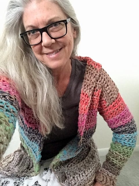 Woman with long grey hair sitting wearing her Kirra Cardigan in size small