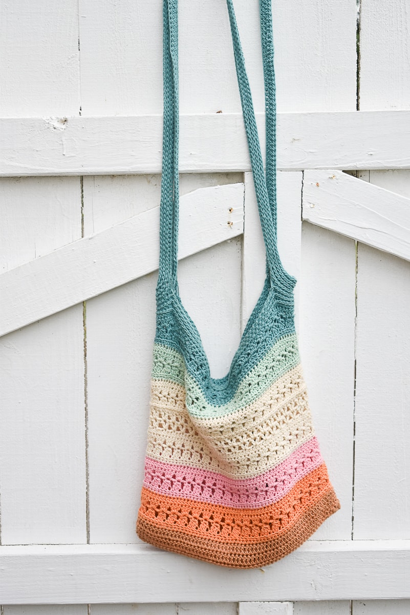 crochet market bag colorful with lion brand yarn on white fence