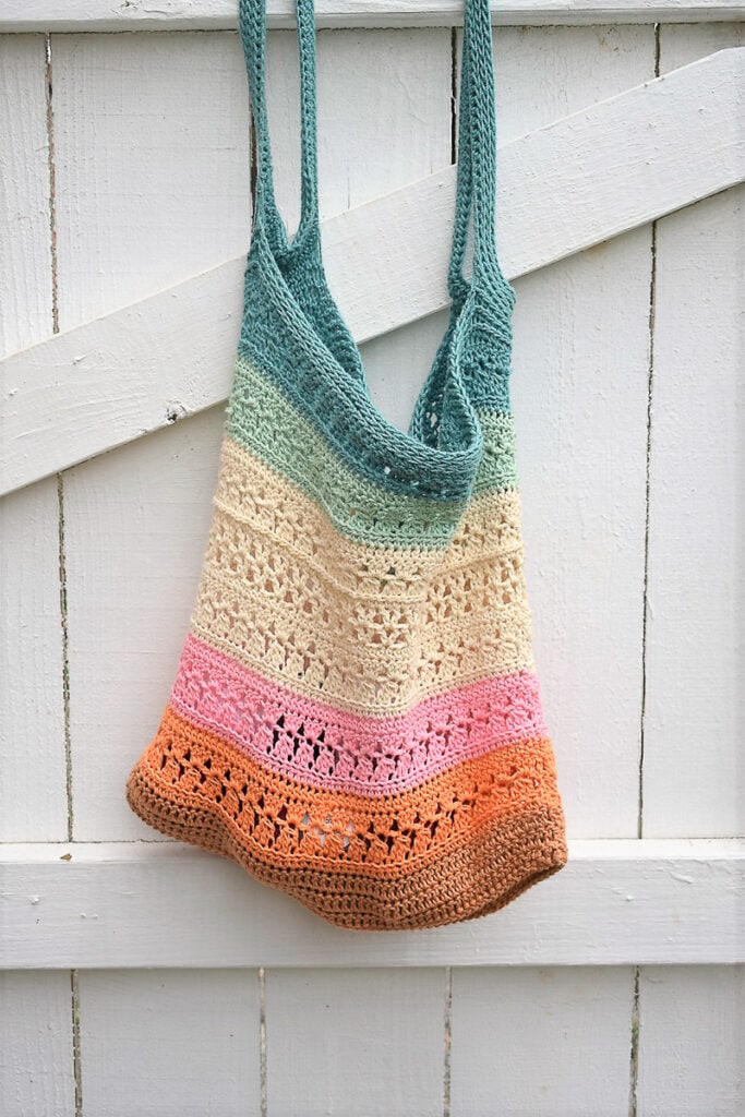 crochet market bag colorful with lion brand yarn on white fence