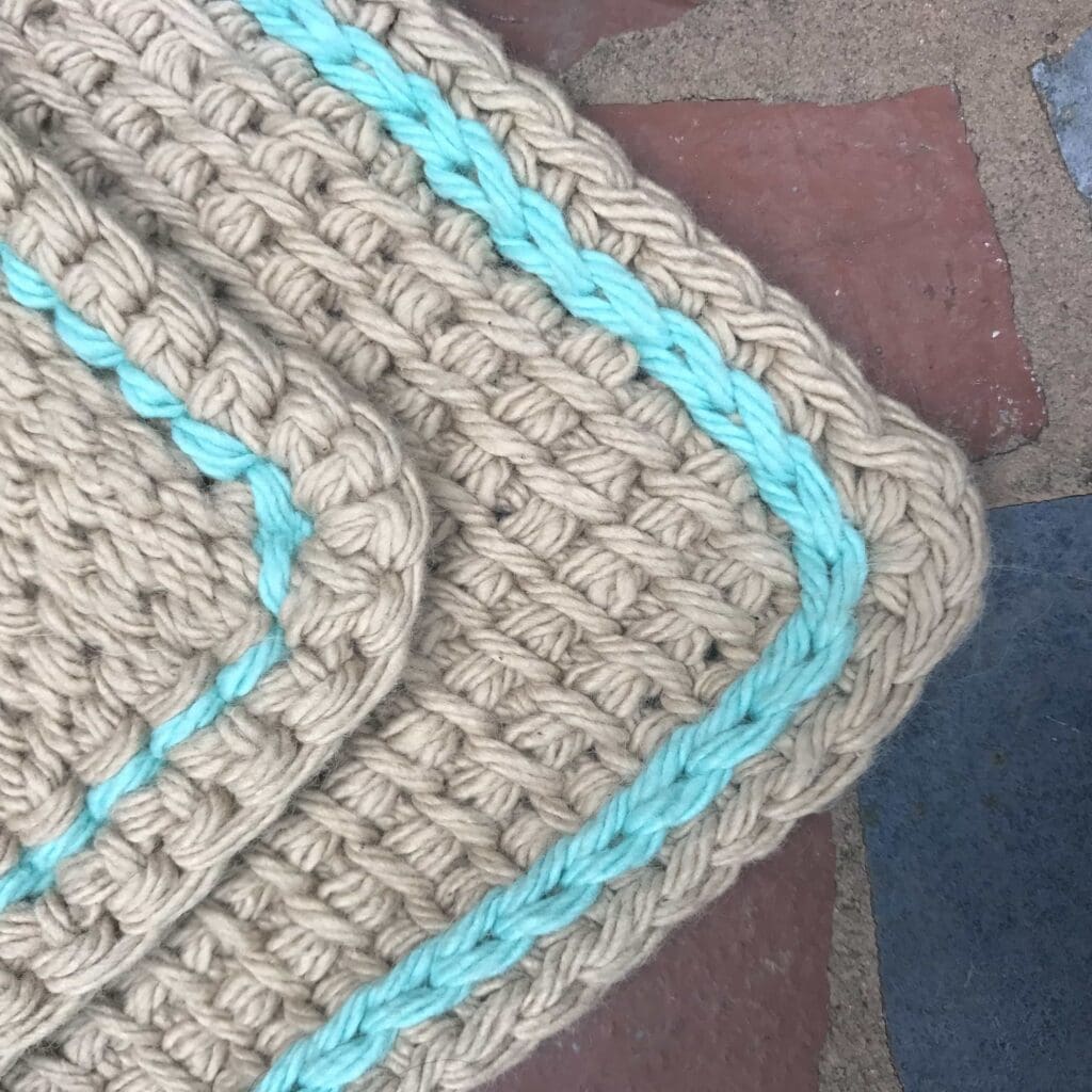 crochet slip stitch tutorial with a Tunisian crochet washcloth with a turquoise slip stitch throughout.