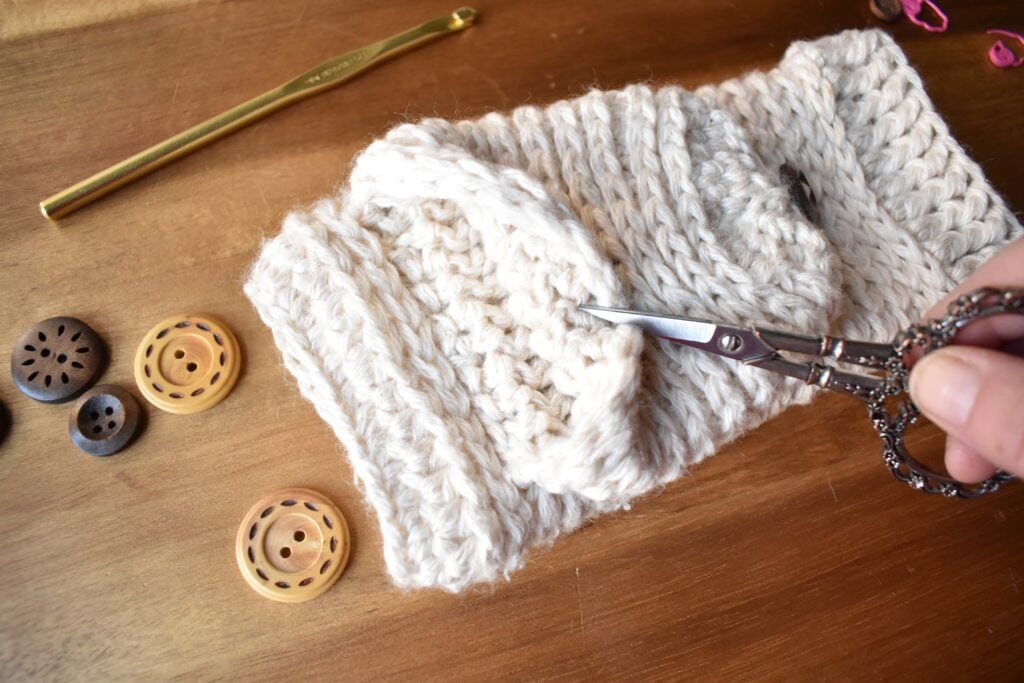 white cozy crochet mittens on a wooden table with wooden buttons and scissors easy crochet mittens pattern