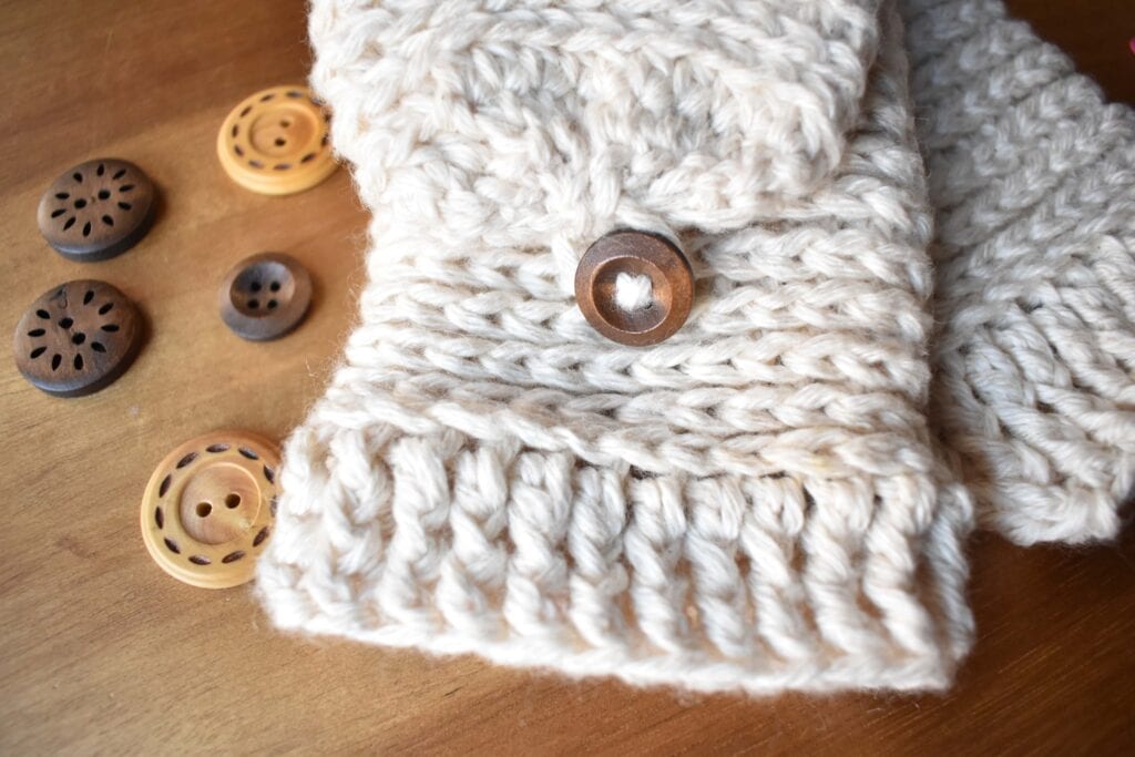 Tabby Star Crochet Mittens Pattern..  White fingerless crochet mittens close up on table with wooden buttons