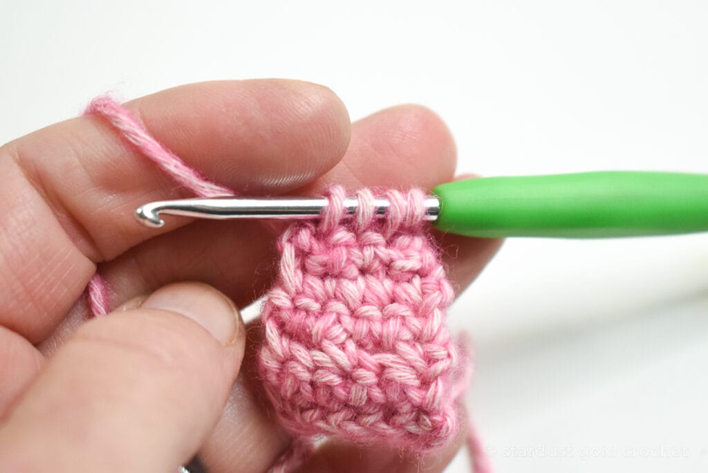 pink yarn with green crochet hook, step 10 of crochet bookmark pattern