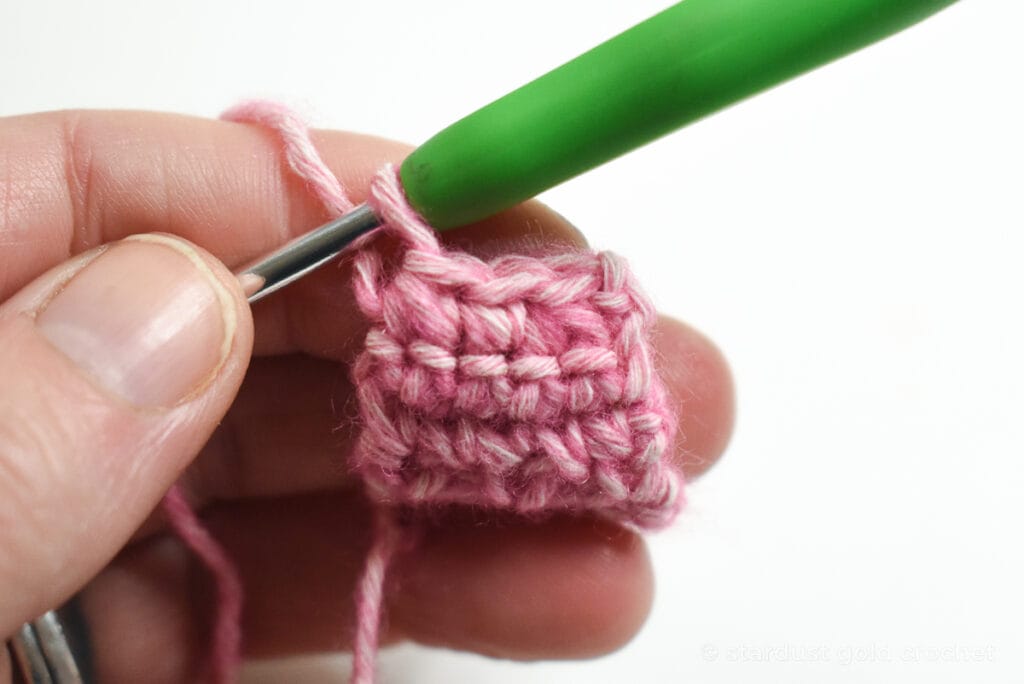 pink yarn with green crochet hook, step 9 of crochet bookmark pattern