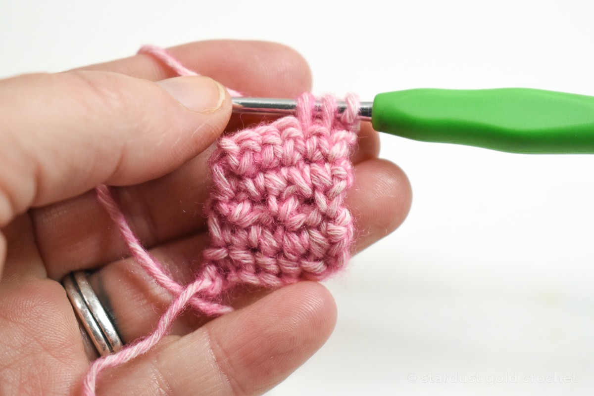 pink yarn with green crochet hook, step 7 of crochet bookmark pattern