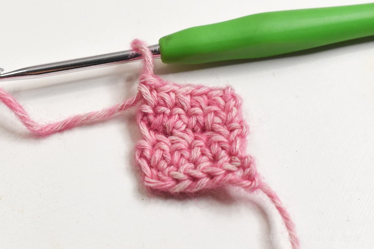 pink yarn with green crochet hook, step 6 of crochet bookmark pattern