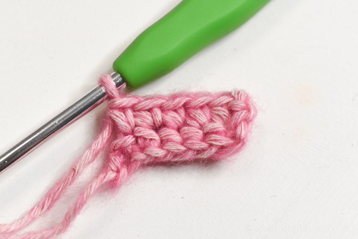 pink yarn with green crochet hook, step 2 of crochet bookmark pattern