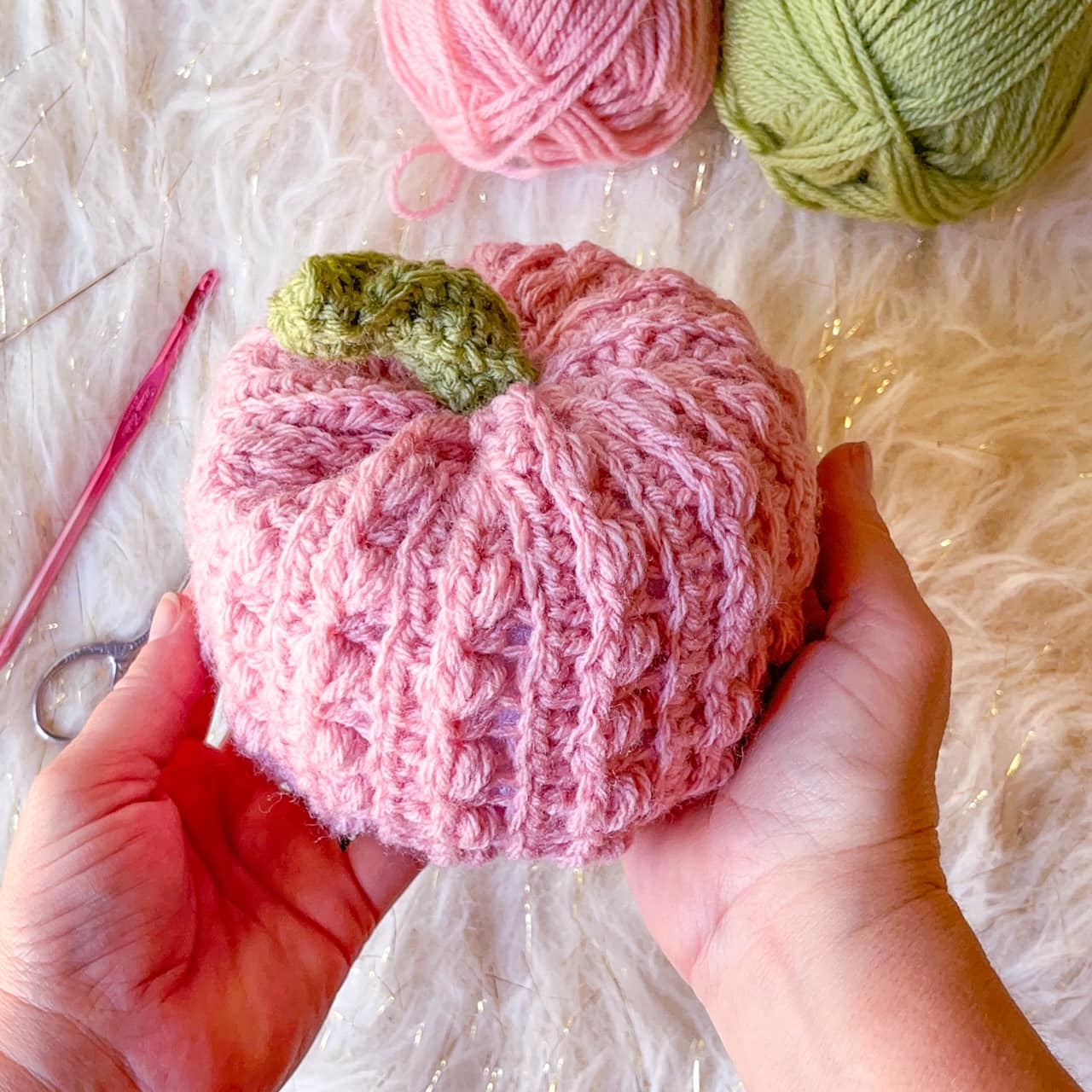 pink crochet pumpkin on white fur table